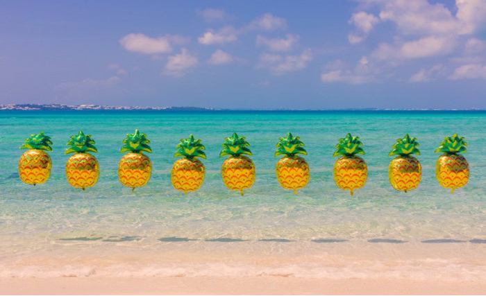 Веселые ананасы на фоне лазурного берега. 