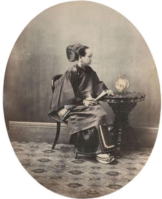 Женщина в традиционном шанхайском костюме сидит за европейским столом.