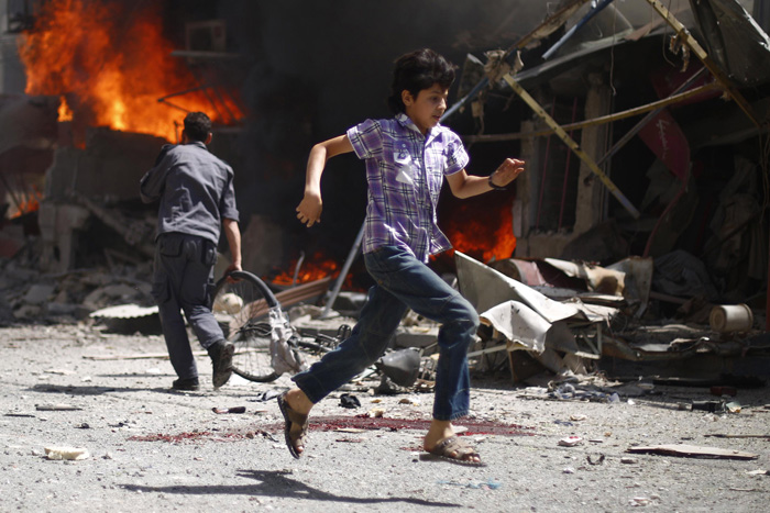 Сирийский юноша пробегает мимо кровавого следа и останков упавшего самолета. 20 августа 2015г.