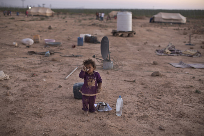 Ребенок пьет чай возле палатки, где живет его семья. Они покинули Сирию и сейчас находятся в Иордании. 26 августа 2015г.