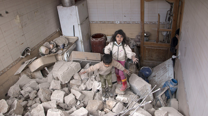 Сирийские дети пробираются по обломкам своего дома. Национальные силы бомбили с воздуха армию повстанцев, город Алеппо. 19 апреля 2015г.