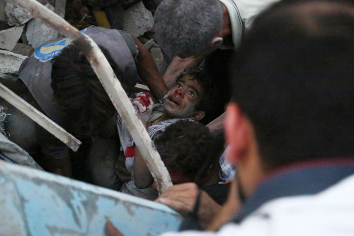Сирийцы спасают раненого мальчика после авиационной атаки в городе Дума. 16 июня 2015г.