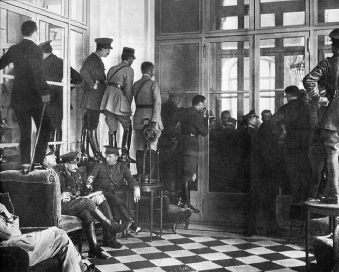 Люди стоят на кушетках, столах и стульях, чтобы увидеть подписание Версальского договора, официально завершившего Первую мировую войну. 28 июня 1919 года.